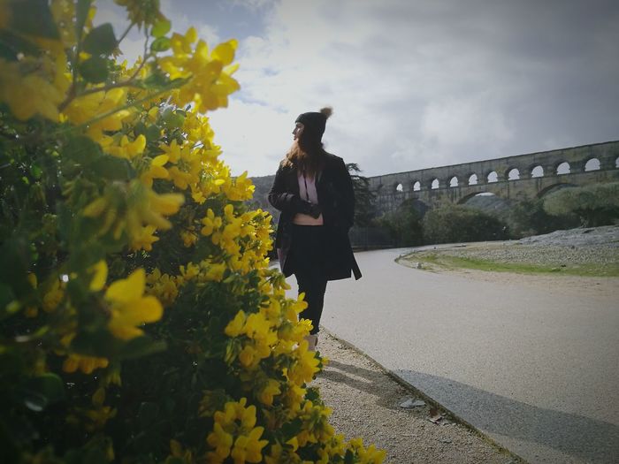 Woman walking by footpath against pont du gard against sky