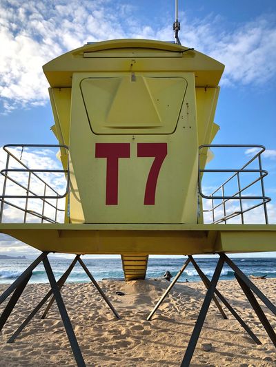 Low angle view of yellow lifeguard hut on beach against sky