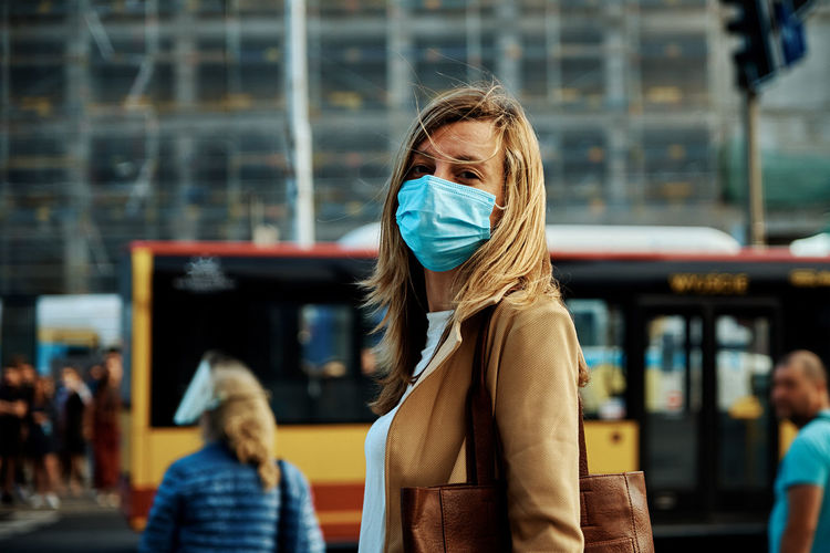 Woman in protective mask walks at city street