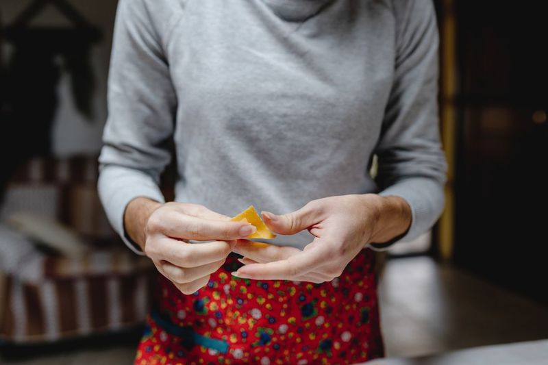 Crop anonymous female standing with traditional italian tortellini in kitchen at home