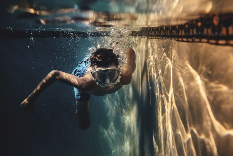 Carefree boy wearing swimming goggles in pool