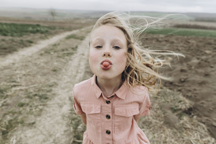 Girl sticking out tongue at agricultural field
