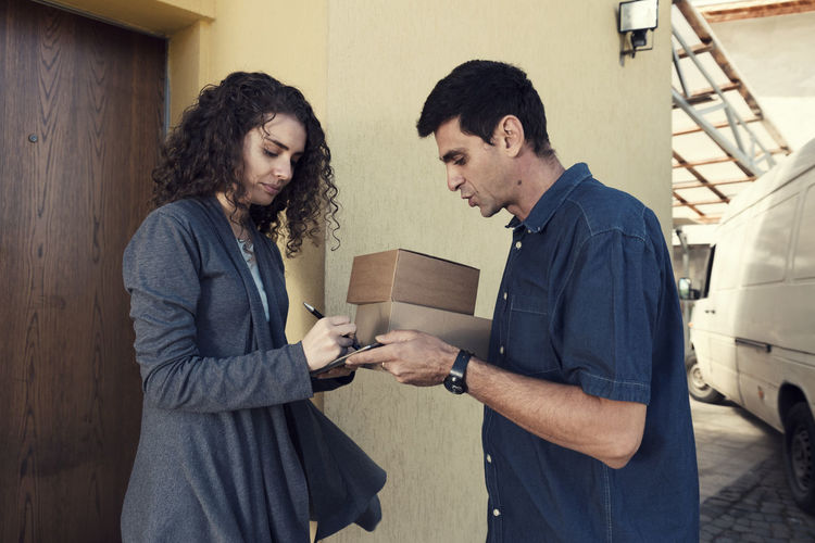 Woman signing on digital tablet held by delivery man