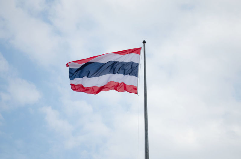 Low angle view of thai flag against cloudy sky
