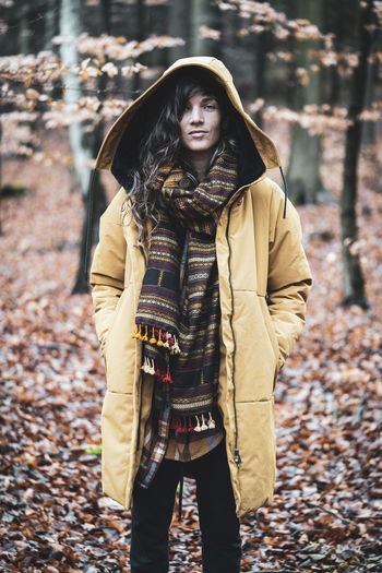 Strong natural woman with curly hair stands empowered in autumn woods