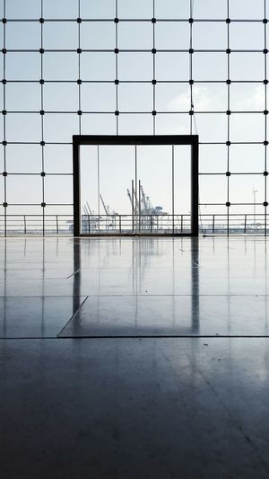 Cranes at port of hamburg seen from building glass
