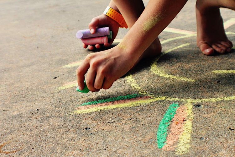 Low section of boy drawing with chalk on street