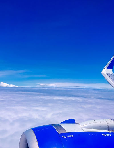 Close-up of airplane flying over sea against blue sky
