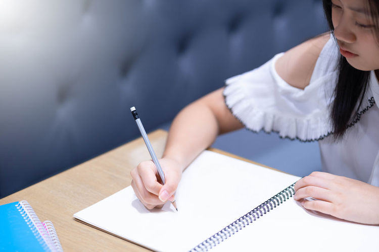 High angle view of girl writing in book