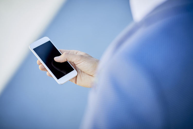 Close-up of businessman using smartphone outdoors in the city