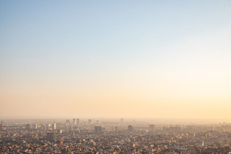 Aerial view of buildings in city against clear sky