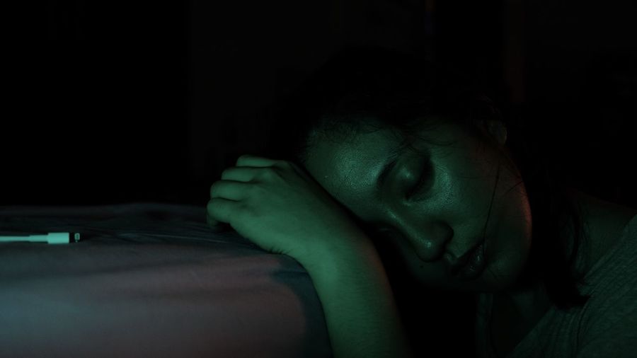 Close-up of young woman with eyes closed leaning on bed
