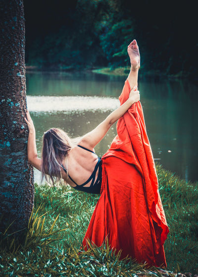 Young ballet dancer wearing red skirt while dancing in forest