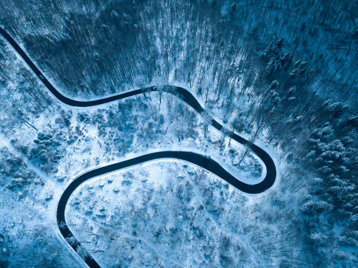 High angle view of winding road amidst trees in forest during winter