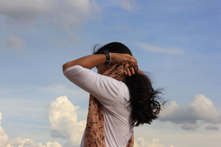Side view of woman standing against sky