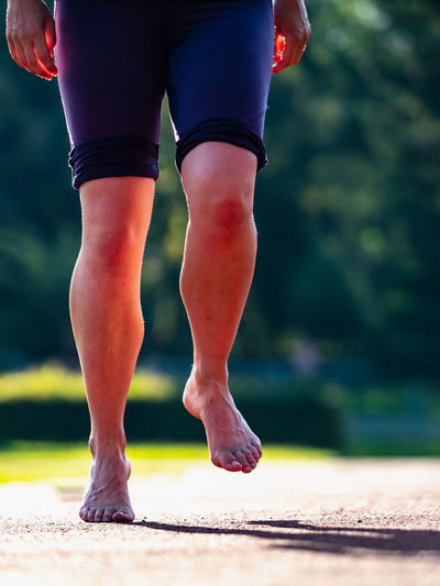 Bare feet of a hard training woman. woman runs along soft surface of running track in short leggings