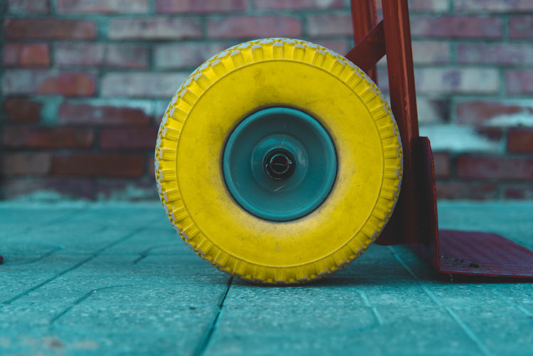 Close-up of yellow wheel against wall