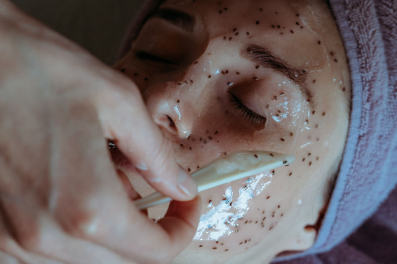 Close-up portrait of young woman applying peel off mask for facial cleansing and spa treatment.