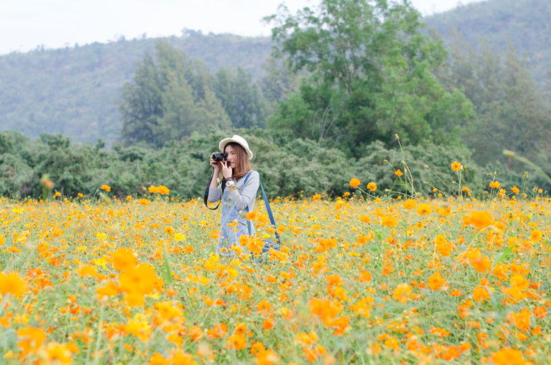 Full length of man standing on yellow flower field