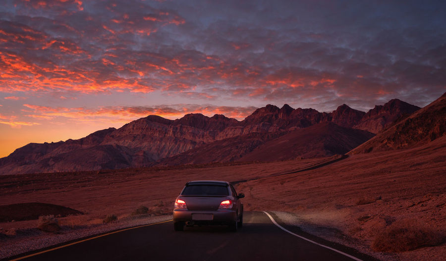 Cars on road against mountains during sunset