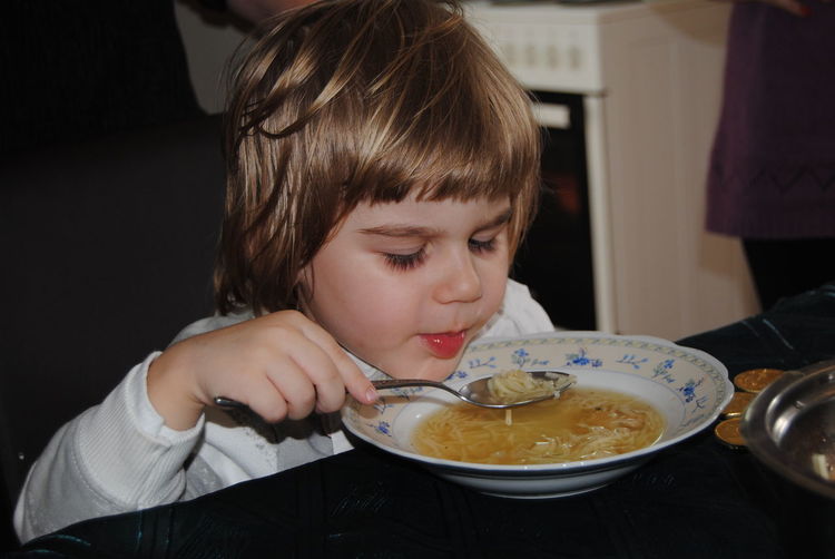 Boy eating noodle soup while sitting at home