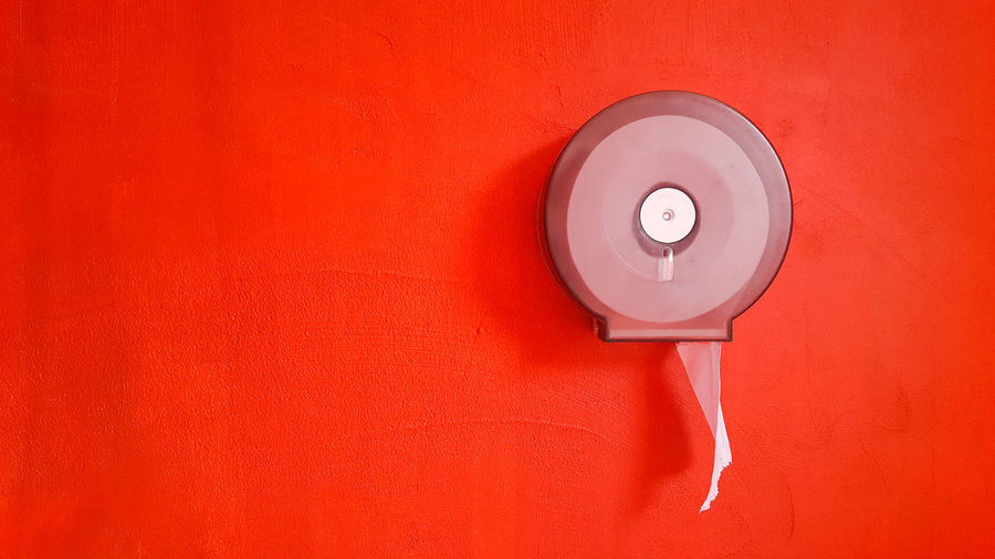 Close-up of toilet paper on red wall
