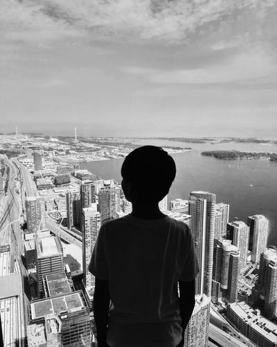 Rear view of boy looking at cityscape against sky