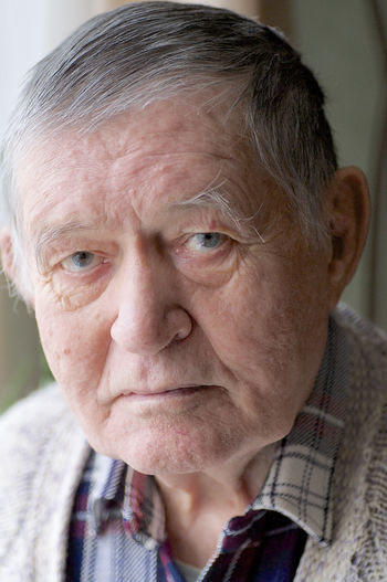Close-up portrait of senior man sitting at home