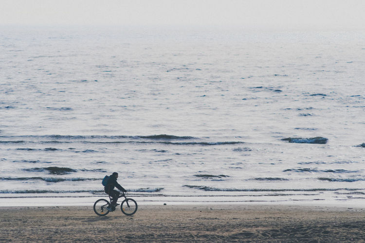 Man riding bicycle on sea shore
