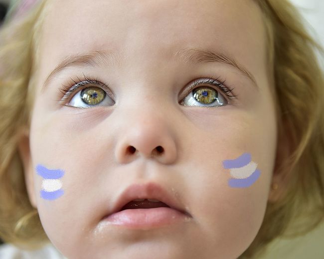 Close-up of cute baby girl with face paint looking away
