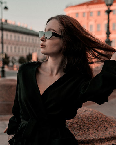 Portrait of young woman wearing sunglasses while standing on street