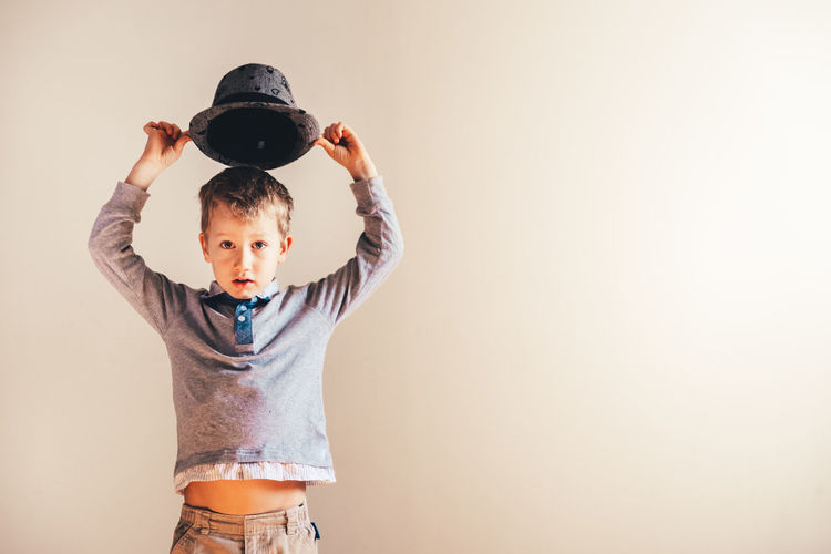 Portrait of cute boy standing against beige background