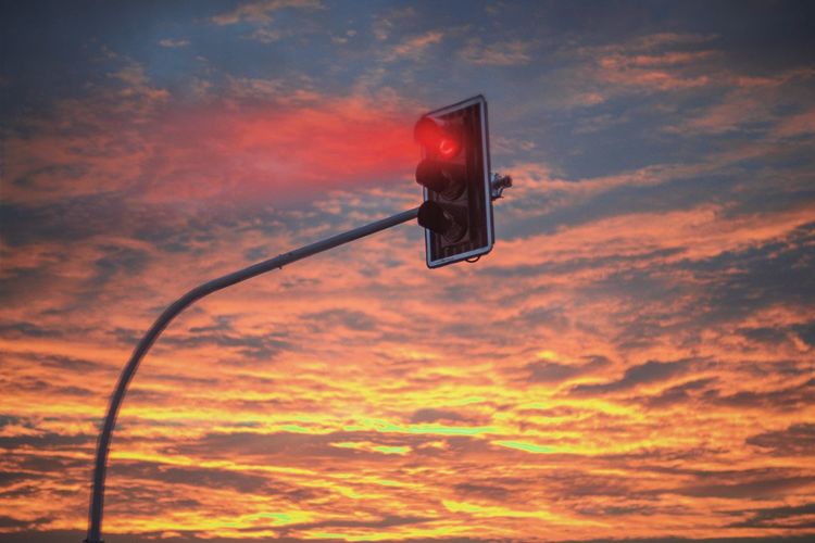 Low angle view of red light against cloudy sky
