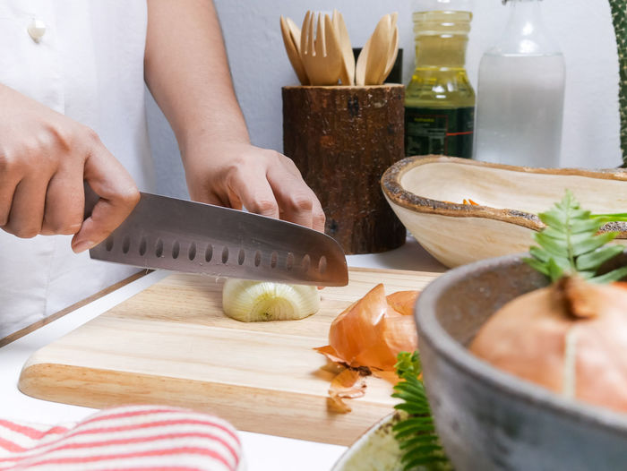 Midsection of person cutting onion on table