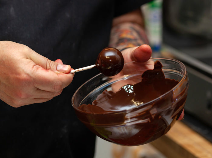 Preparation of cake pops. sweets in black chocolate glaze on a stick