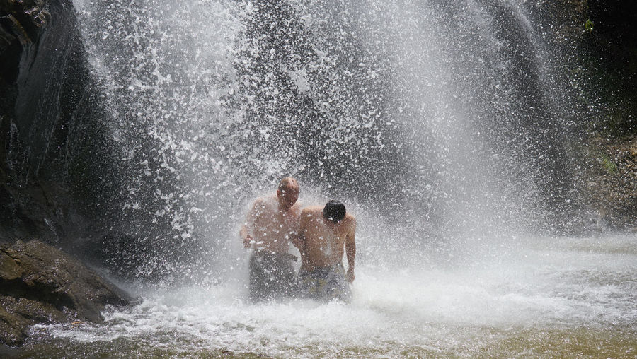 Men enjoying bathing in waterfall
