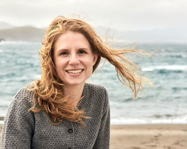 Portrait of smiling woman with long hair at beach