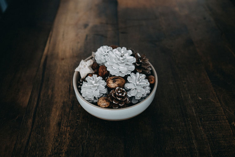 High angle view of pine cones and walnuts in bowl on table during christmas