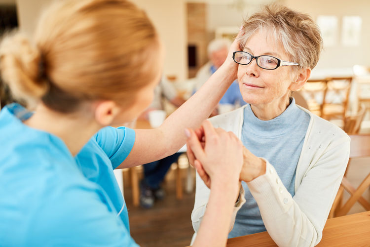 Nurse consoling senior woman at rehab center