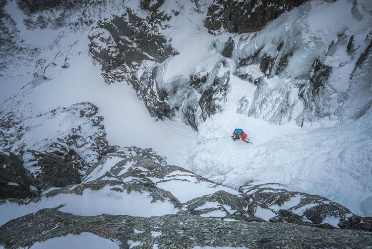 An alpine ice climber ascends a frozen gully in maine