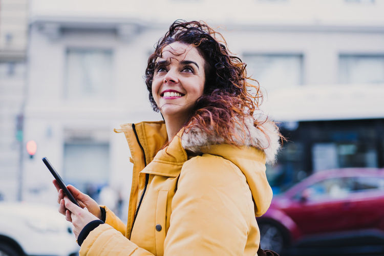 Portrait of smiling woman standing on mobile phone