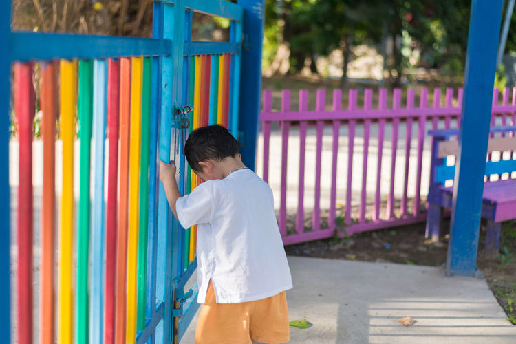 Boy standing by closed park gate
