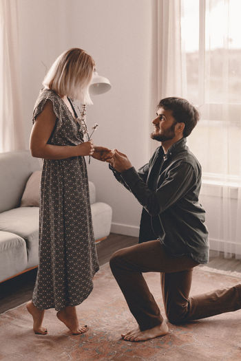 Smiling man proposing girlfriend at home