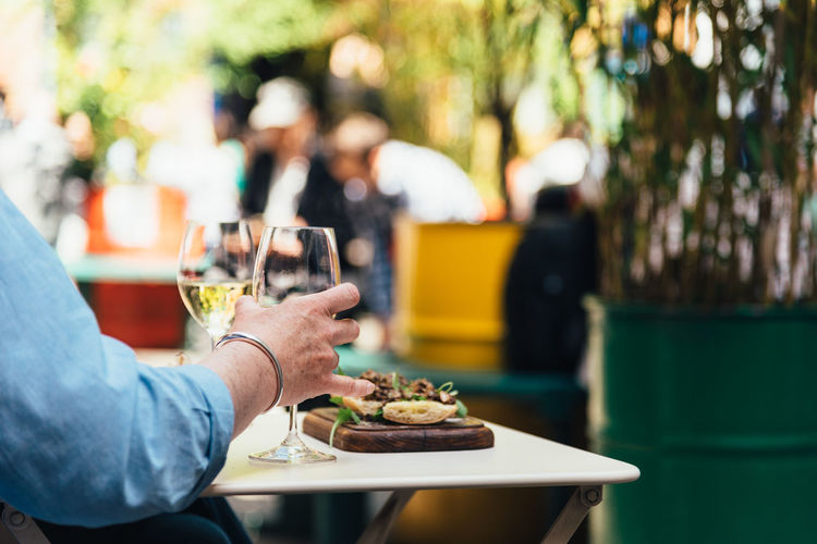 Woman enjoying meal with white wine in a trendy shopping area sitting on a terrace.