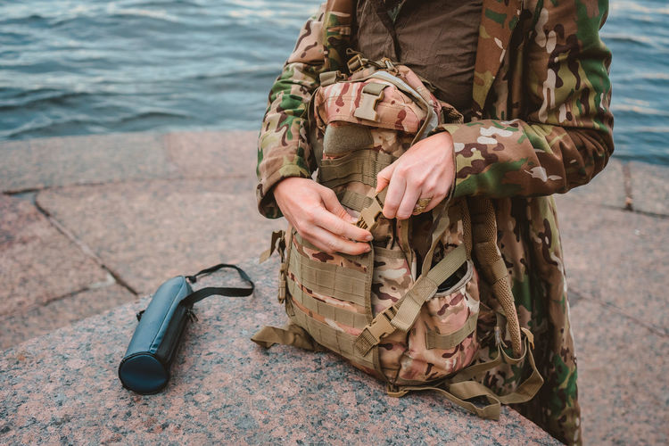Military-colored backpack with pockets. the girl's hands fasten the travel bag