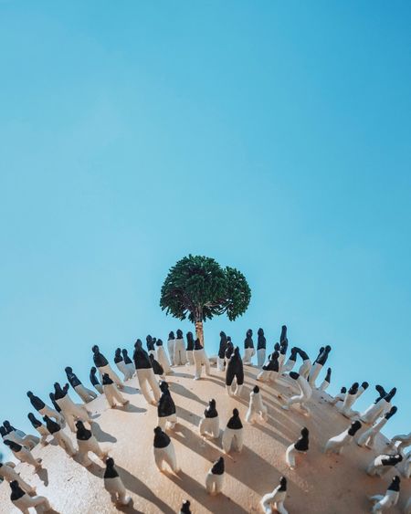 Artificial tree surrounded by figurines against clear blue sky