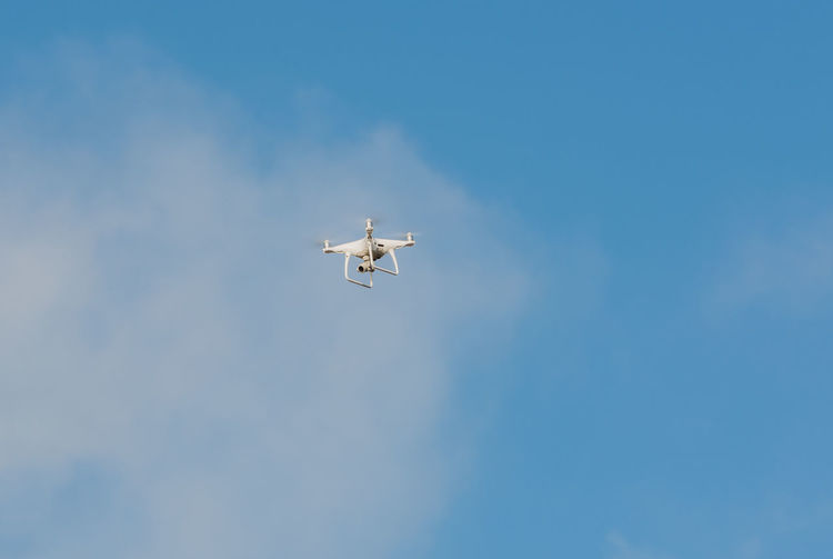 Low angle view of drone flying against sky