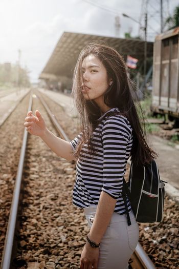Young woman looking down while standing on railroad track