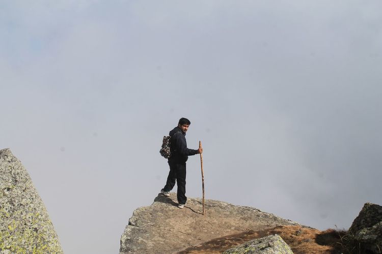 Full length of man standing on rock against clear sky