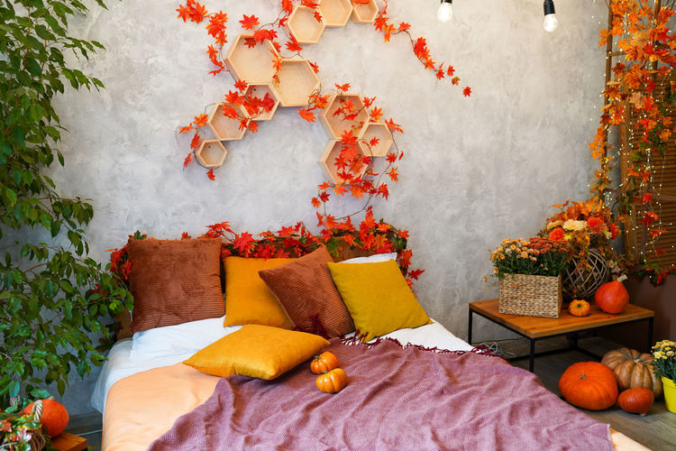 Home autumn decor. cozy fall bedroom interior bed with orange pillows and pumpkins, autumn 